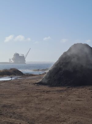 En stor haug med kompost på Årabrot miljøpark. I bakgrunnen ser vi plattformen Johan Sverdrup P2 på vei ut fra Haugesund.