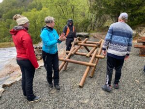 HIM-medarbeidere bygger en liten bro av trestokker som en del av teambuilding i Skånevik