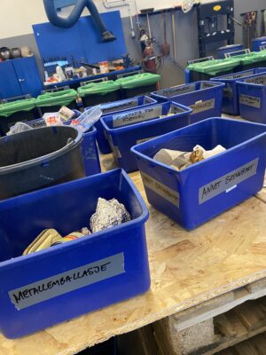 Mange ulike beholdere der avfallet ble sortert under plukkanalysen. Det står "metallemballasje", "annet brennbart" osv. på de ulike beholderne.